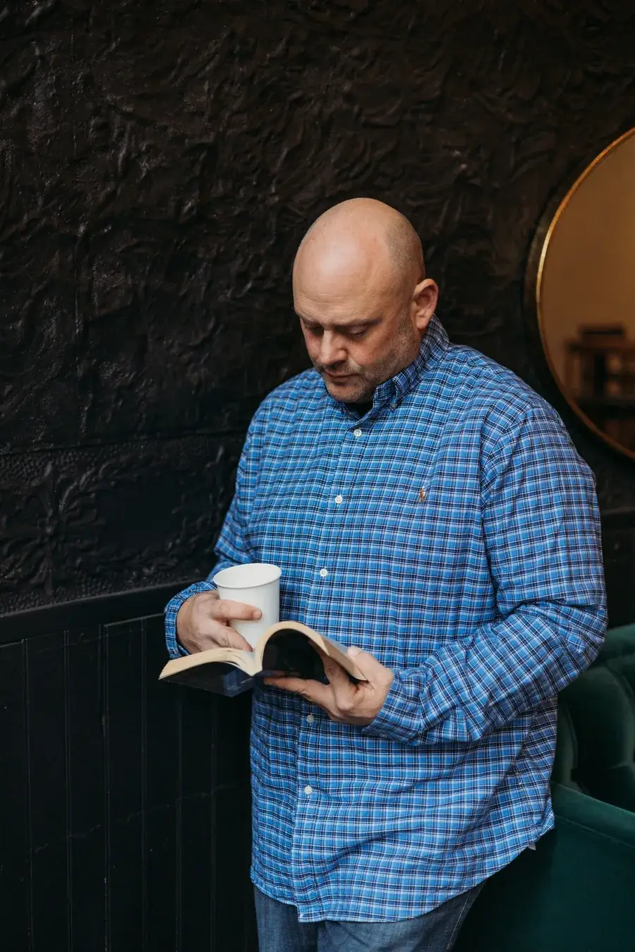 Jeremy Kean reading a book with a coffee in hand
